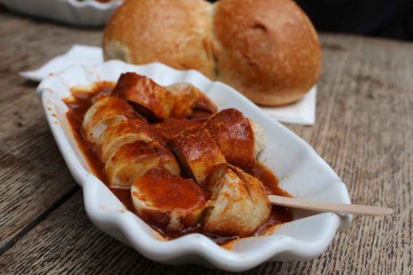 Currywurst – xúc xích cắt lát chan sốt cà ri đặc trưng – là món ăn đường phố biểu tượng của Berlin. Người Berlin tiêu thụ hơn 70 triệu khẩu phần mỗi năm, giá chỉ khoảng €3–5 tại các quầy vỉa hè. Đây là món ăn đầu tiên bạn nên thử khi du lịch đến Berlin.